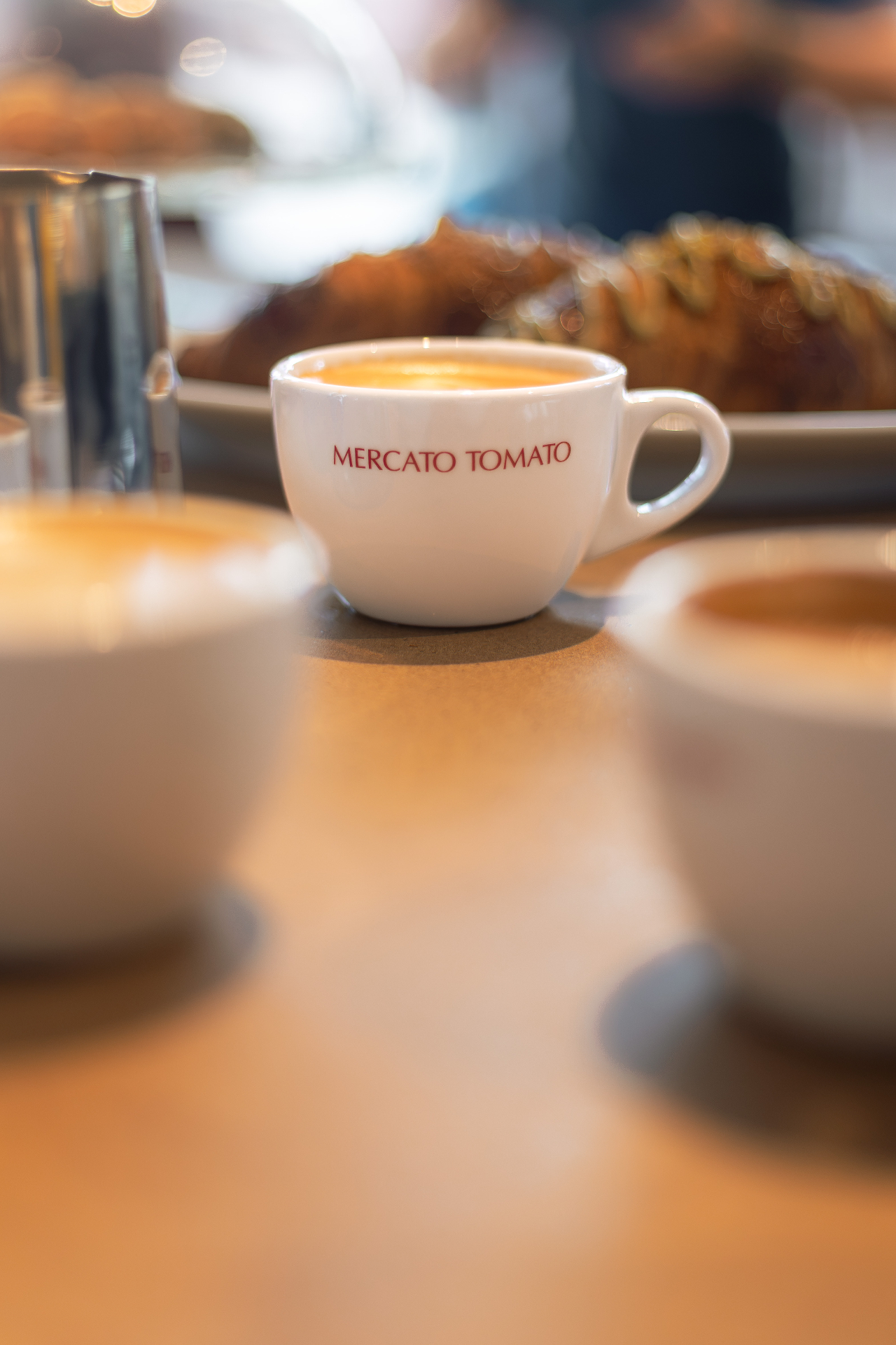 Espressokopje met het Mercato Tomato logo op een houten tafel